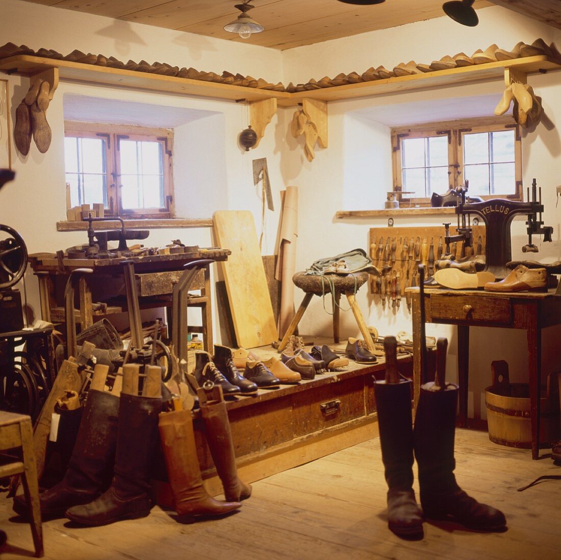 Boots and shoes in traditional-style rustic cobbler's workshop with small lattice windows