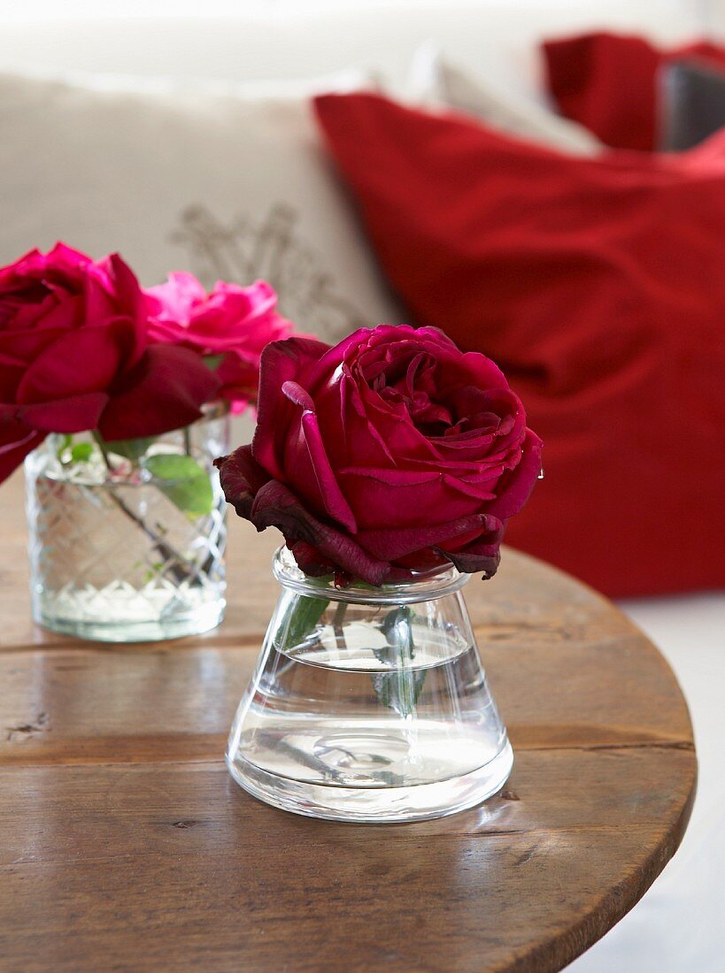 Romantic red roses in small glass vases on rustic wooden table