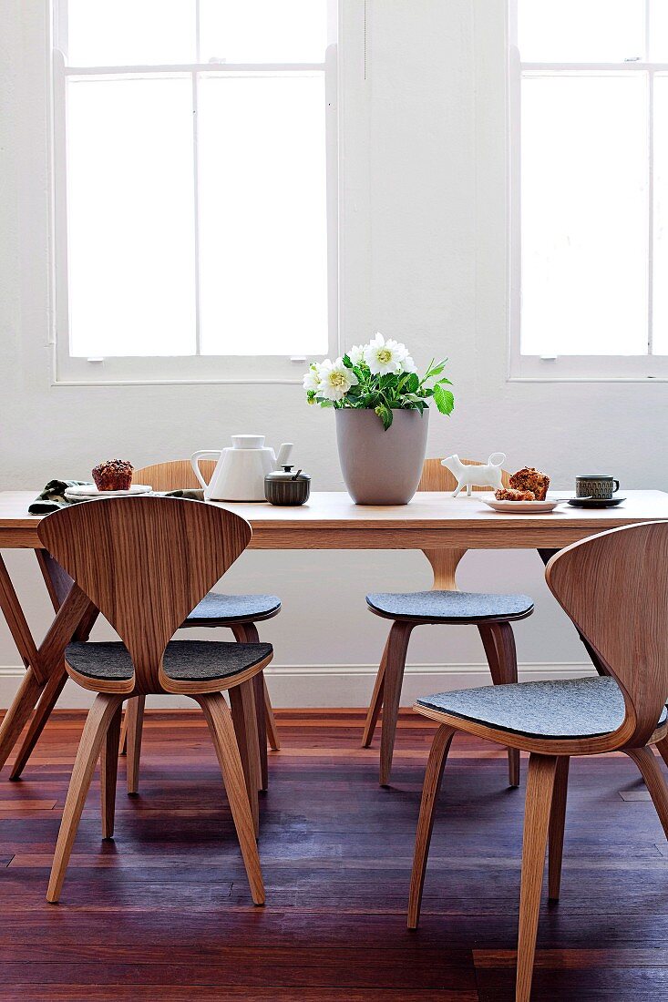 Tea service on wooden table and curved, laminated timber chairs with grey felt seats