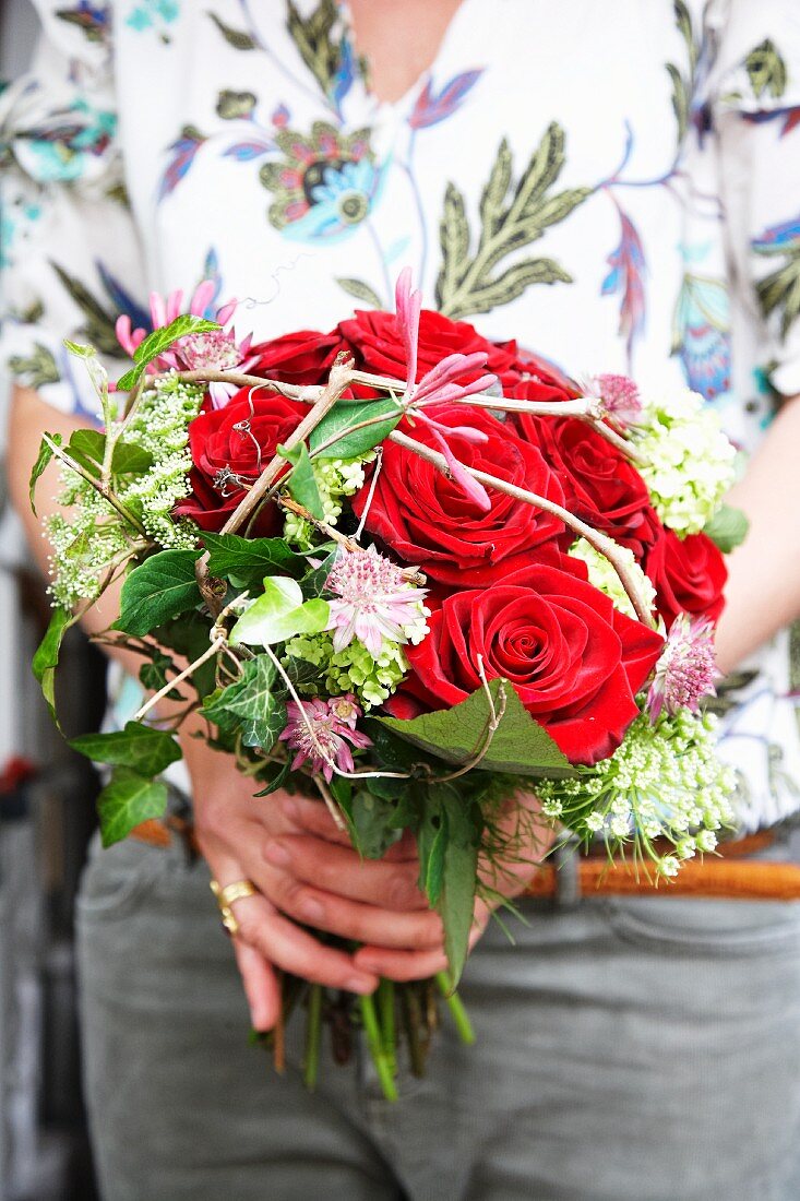 Hands holding bouquet with red roses