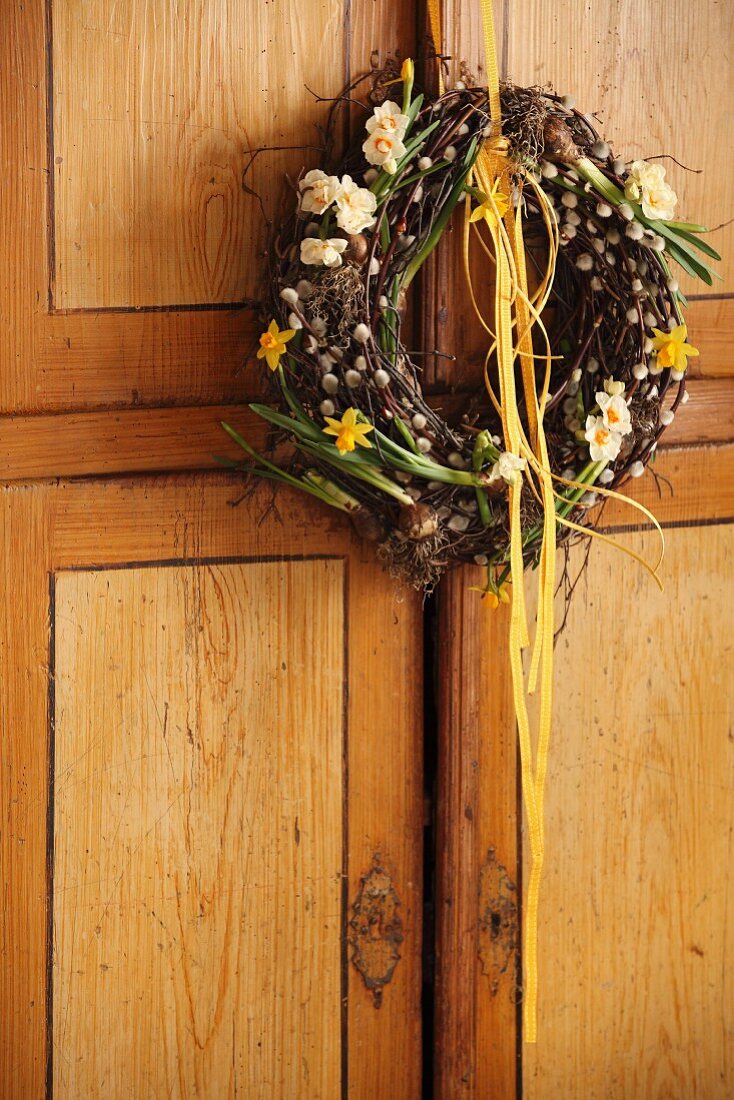Spring wreath of birch twigs, pussy willow and spring flowers hanging on cupboard door