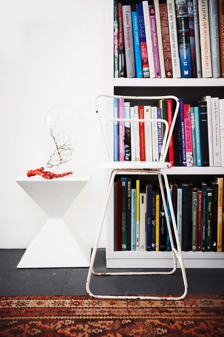 White bookcase, white, retro side table and worn, white metal chair