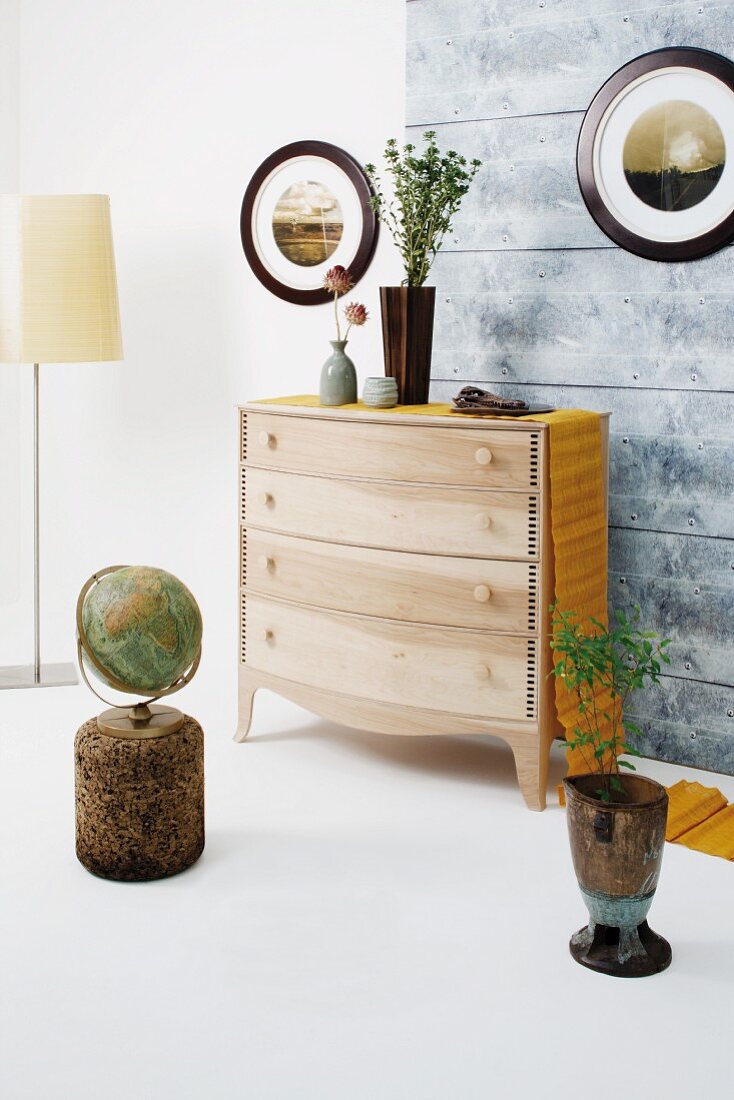 Wooden chest of drawers with yellow runner surrounded by objets d'art with natural motifs