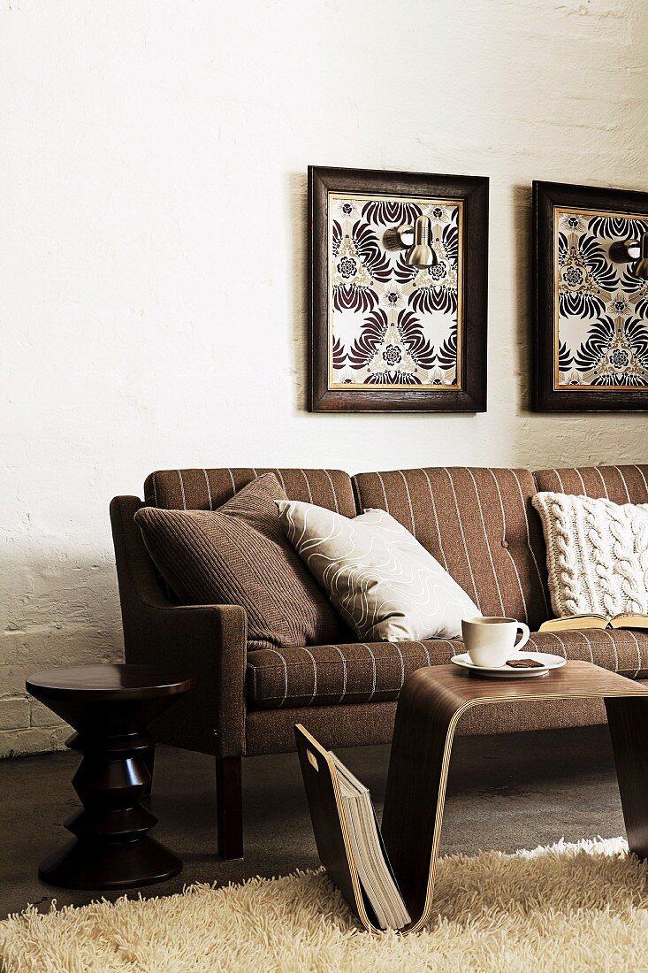 Brown striped sofa, small side table and hand-crafted wall lamps in picture frames