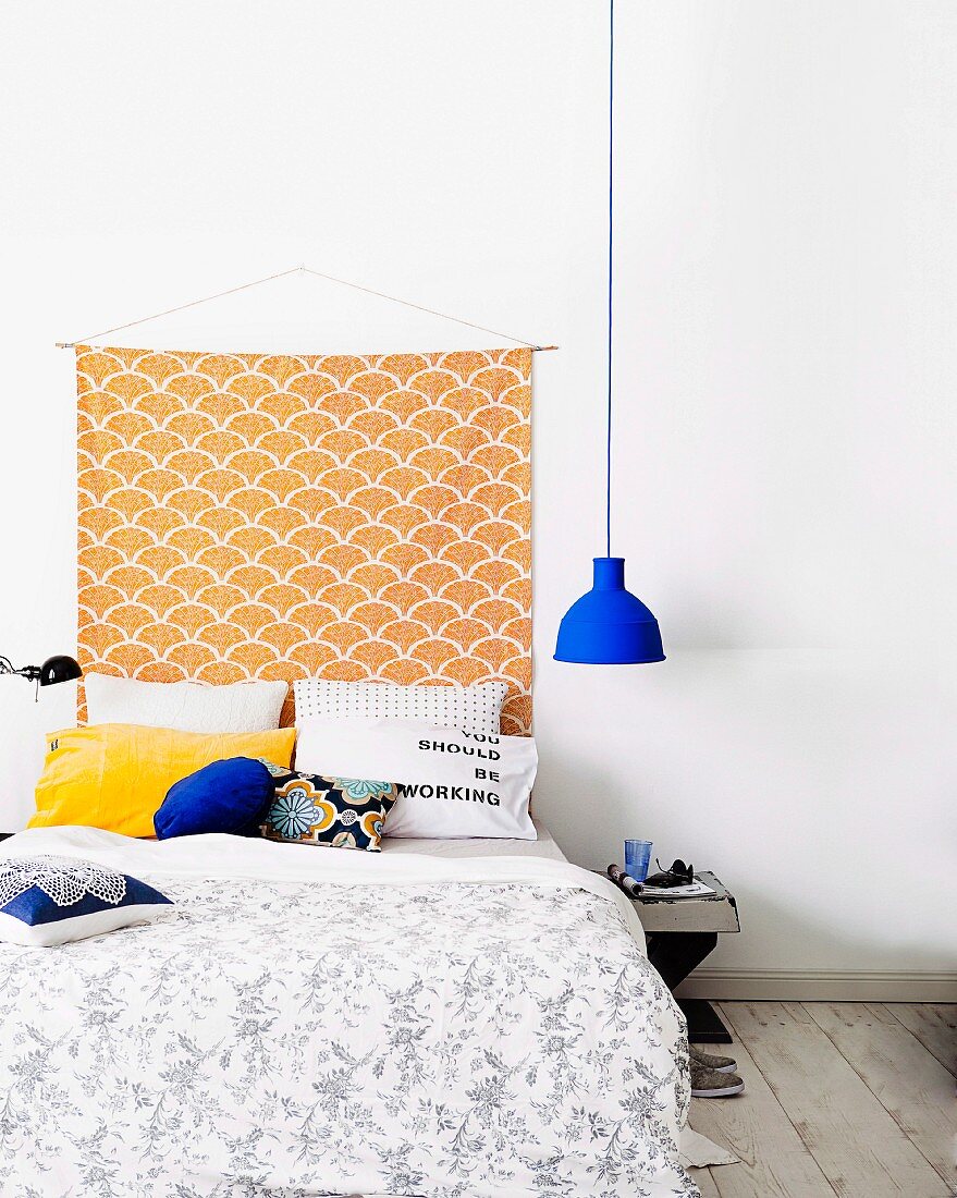 Selbstgemachter Wandbehang über gemütlichem Doppelbett an weißer Wand