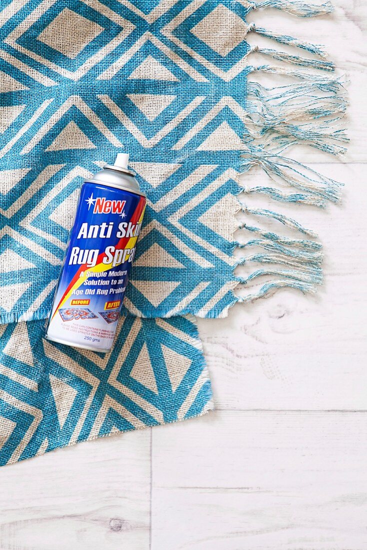 Spray can on blue-patterned, fringed fabric