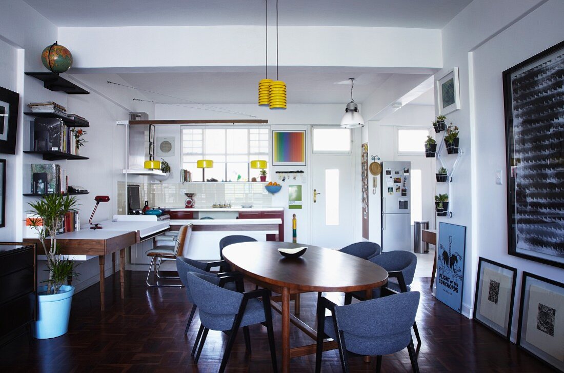Ovaler Essplatz mit skandinavischen Vintage Möbeln in offenem Wohnraum mit Schreibtisch und Küche im Hintergrund