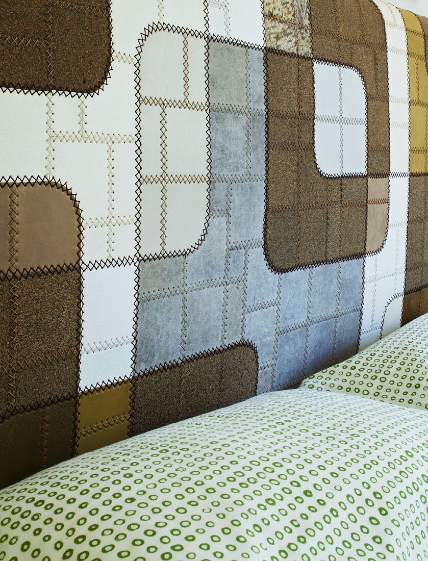 Feines Leder-Patchwork in kontrastreichen Naturfarben am Kopfteil eines Doppelbetts; Kissen mit kleinem, grünem Kreismuster