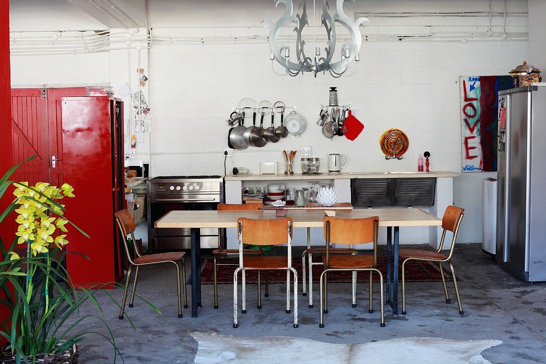 Tisch und Stühle im Retrostil vor Küchenzeile, an der Seite roter Schrank in loftartigem Wohnraum