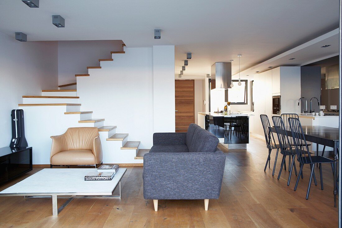 Open-plan living area in architect-designed house with minimalist furnishings and staircase without handrail