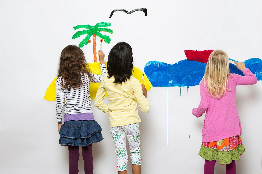 Drei Kinder malen Meer & Insel an eine Wand