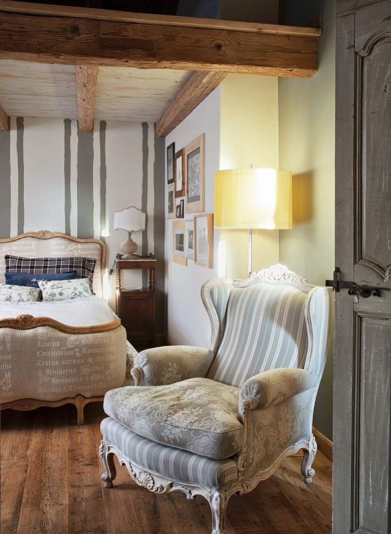 Rustikales Schlafzimmer mit Rokoko-Sesseln, Stehleuchte und antikem französischen Bett