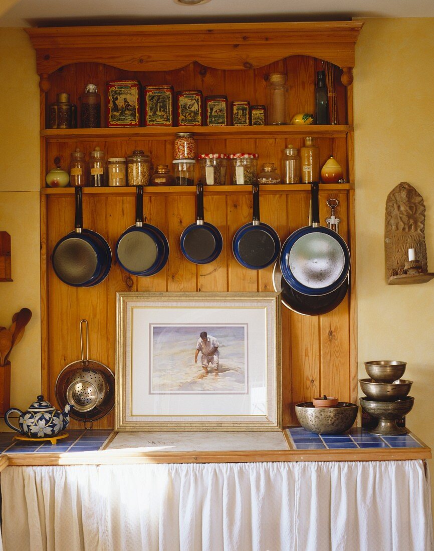 Aufgehängte Töpfe und Pfannen sowie Küchenutensilien in Küchenschrank aus Kiefernholz