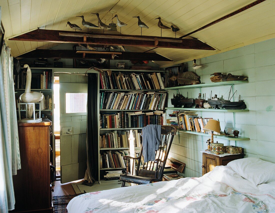 Schlafraum mit Doppelbett, Bücherwand, Wandregalen & maritimer Deko