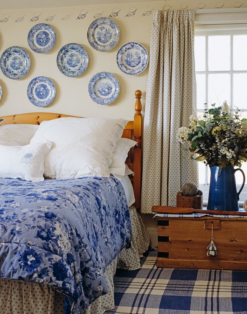Schlafraum in Blau-Weiß mit Sammlung von Porzellantellern an der Wand über dem Bett