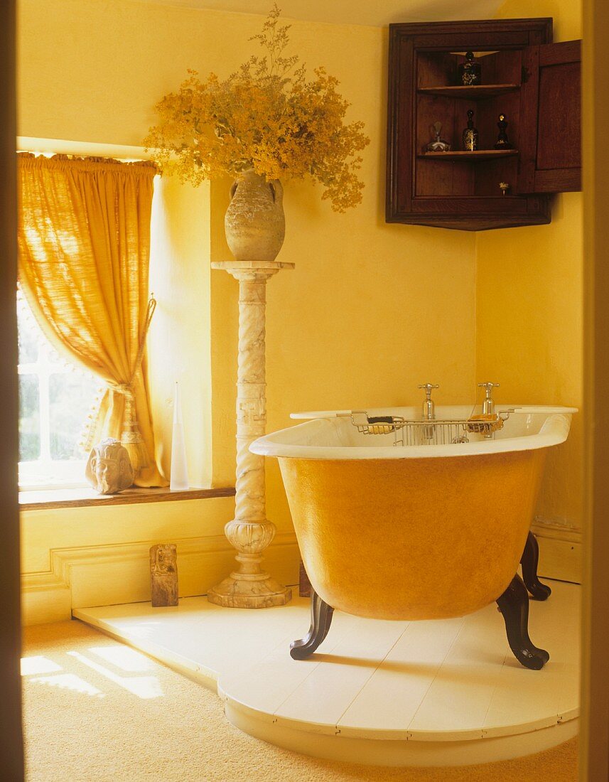 Gelbe freistehende Badewanne auf Podest in Bad mit gelben Wänden & Vorhängen