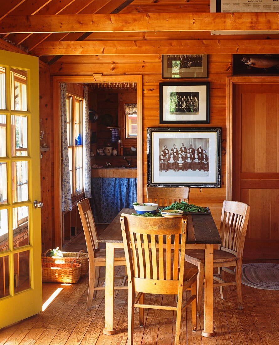 Esstisch und Stühle in Holzhütte mit offener Haus- und Küchentür