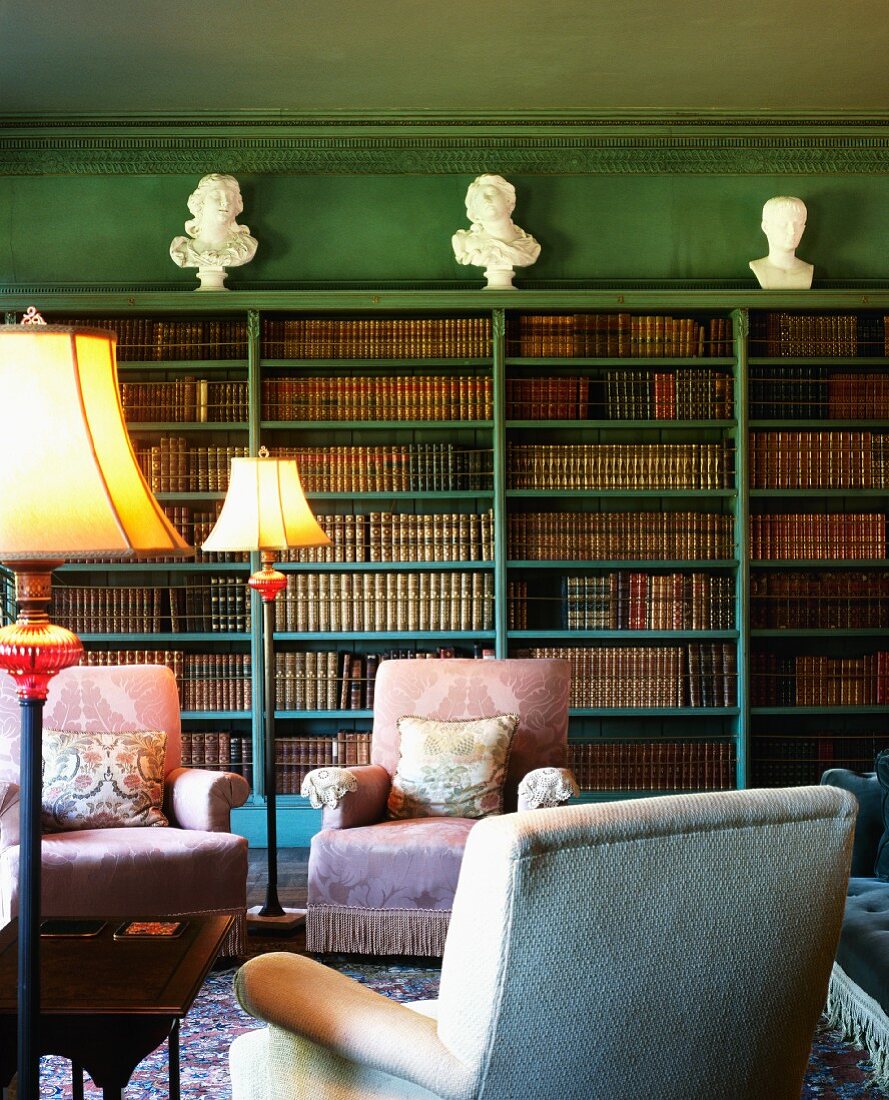 Grün getönte traditionelle Bibliothek mit Polstersesseln vor Bücherregalen