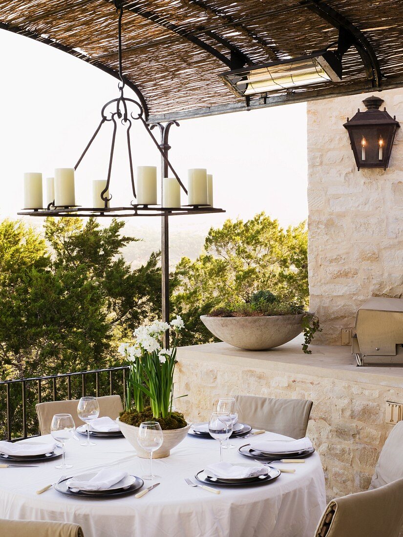 Mediterrane Terrasse mit gedecktem Tisch und an Pergoladecke gehängter Kerzenleuchter