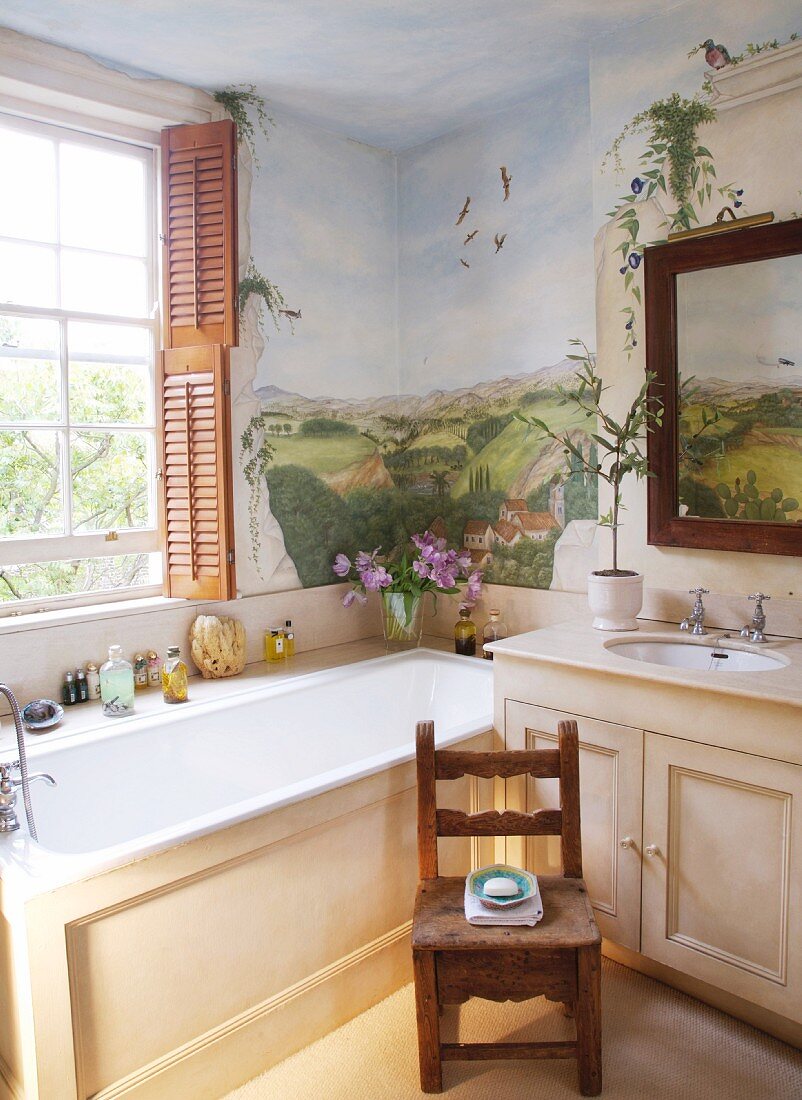 Badezimmerecke im Landhausstil - eingebaute Badewanne am Fenster vor bemalter Wand mit Landschaftsmotiv