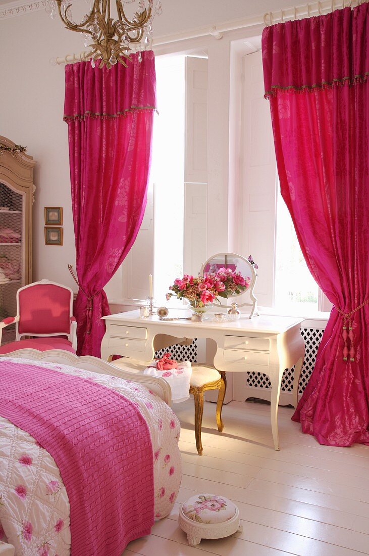 Weisser Schminktisch im Vintagestil am Fenster mit pinkfarbenem, gerafftem Vorhang im Boudoir