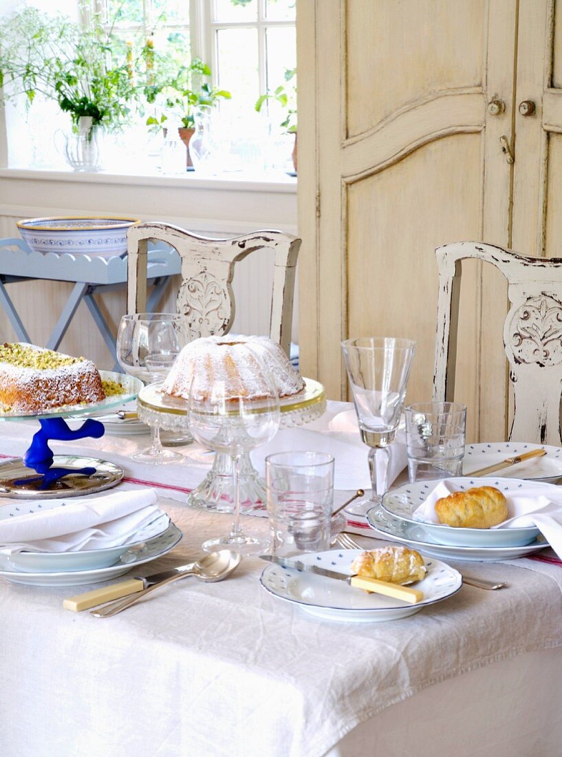 Weiß gedeckter Esstisch mit Kuchenstücken auf Teller in ländlichem Esszimmer