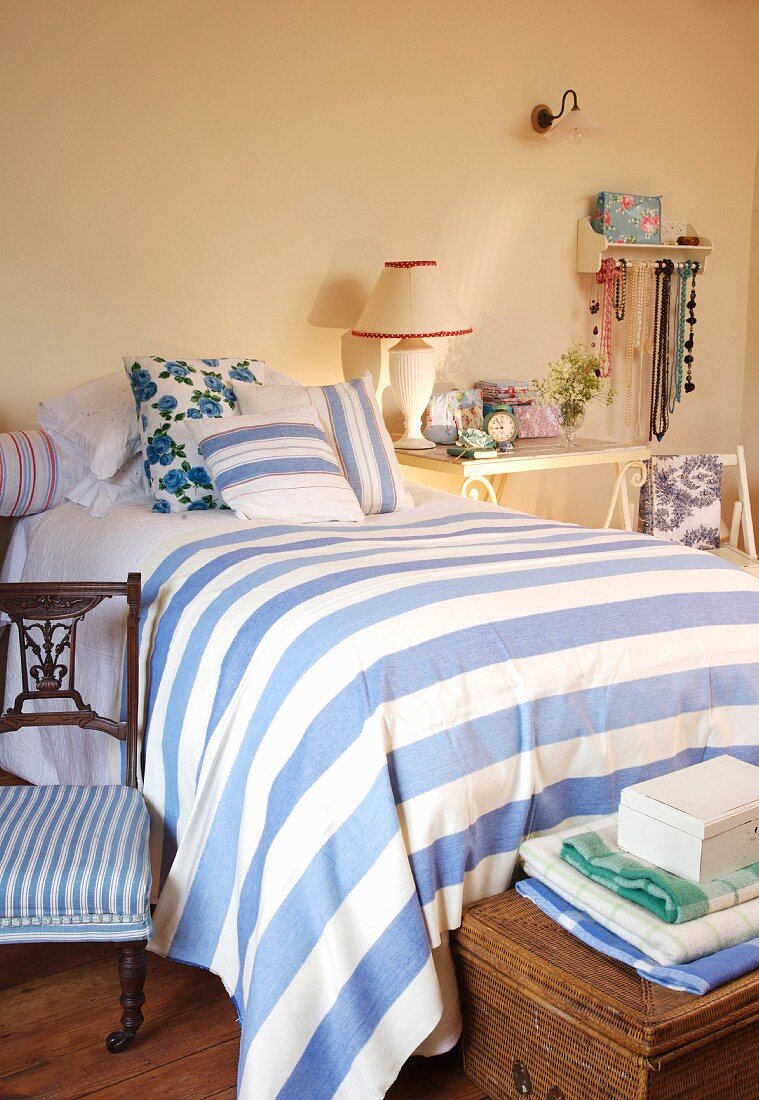 Blau gestreifte Tagesdecke auf Einzelbett in ländlichem Schlafzimmer