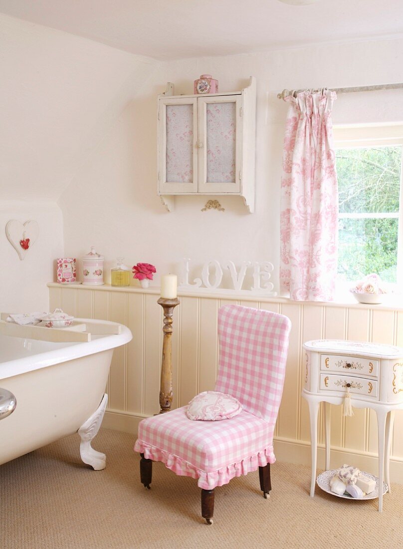 Stuhl mit rosa weiss karierter Husse neben Vintage Badewanne in ländlichem Bad