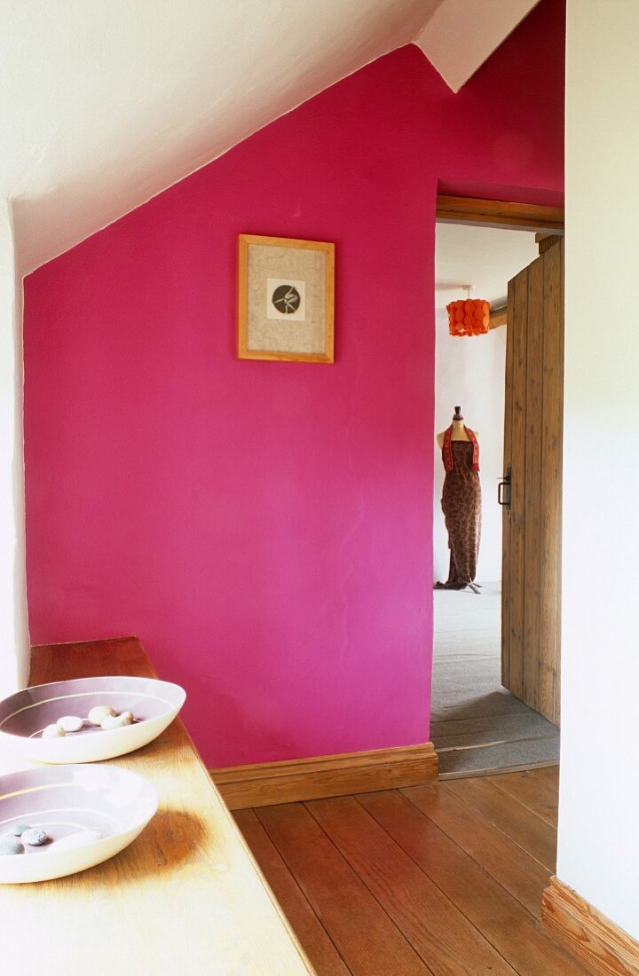 Pinkfarbene Wand in rustikalem Dachgeschoss Flur und Blick durch offene Tür auf Schneiderpuppe