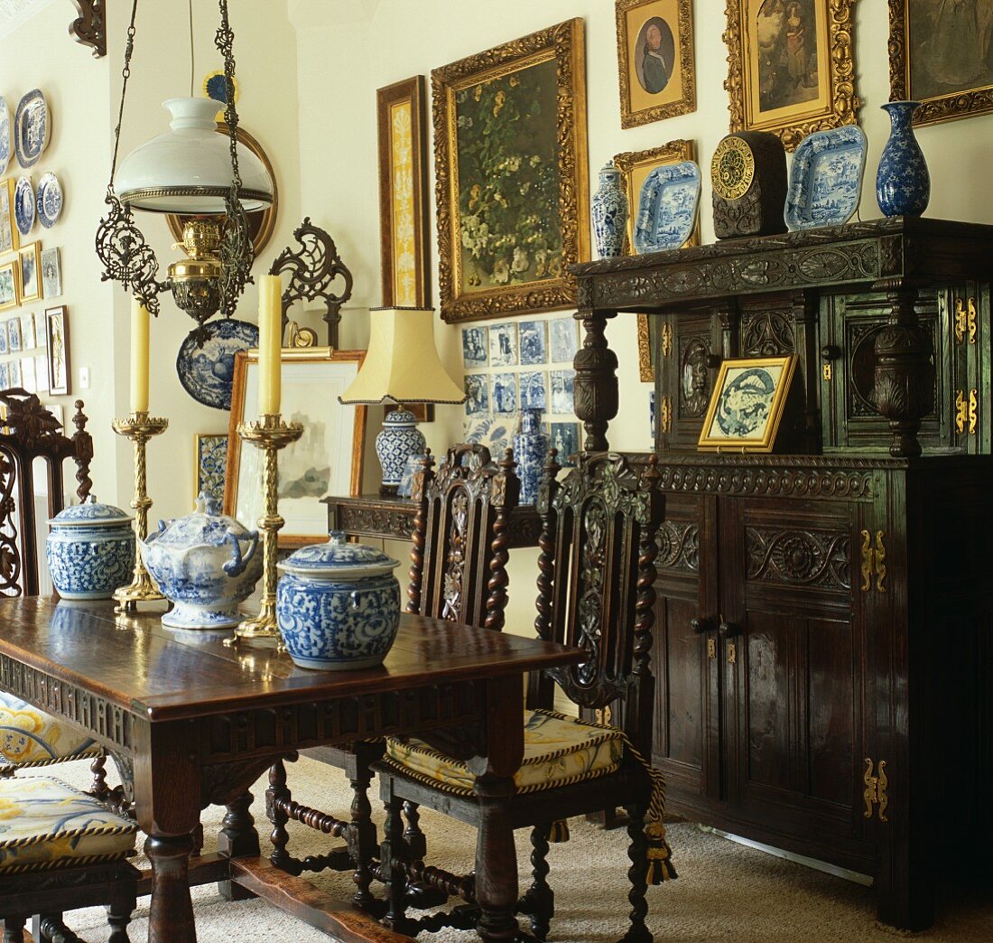 Traditionelles Esszimmer mit dunklen geschnitzten Eichen Stühlen um Tisch mit chinesischen Vasen vor Anrichte mit Aufsatz