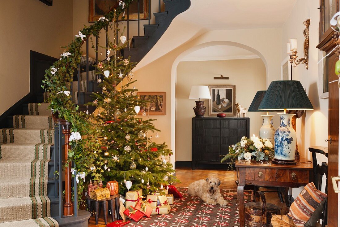 Offenes Foyer eines traditionellen Landhauses mit geschmücktem Weihnachtsbaum und dekoriertem Treppengeländer