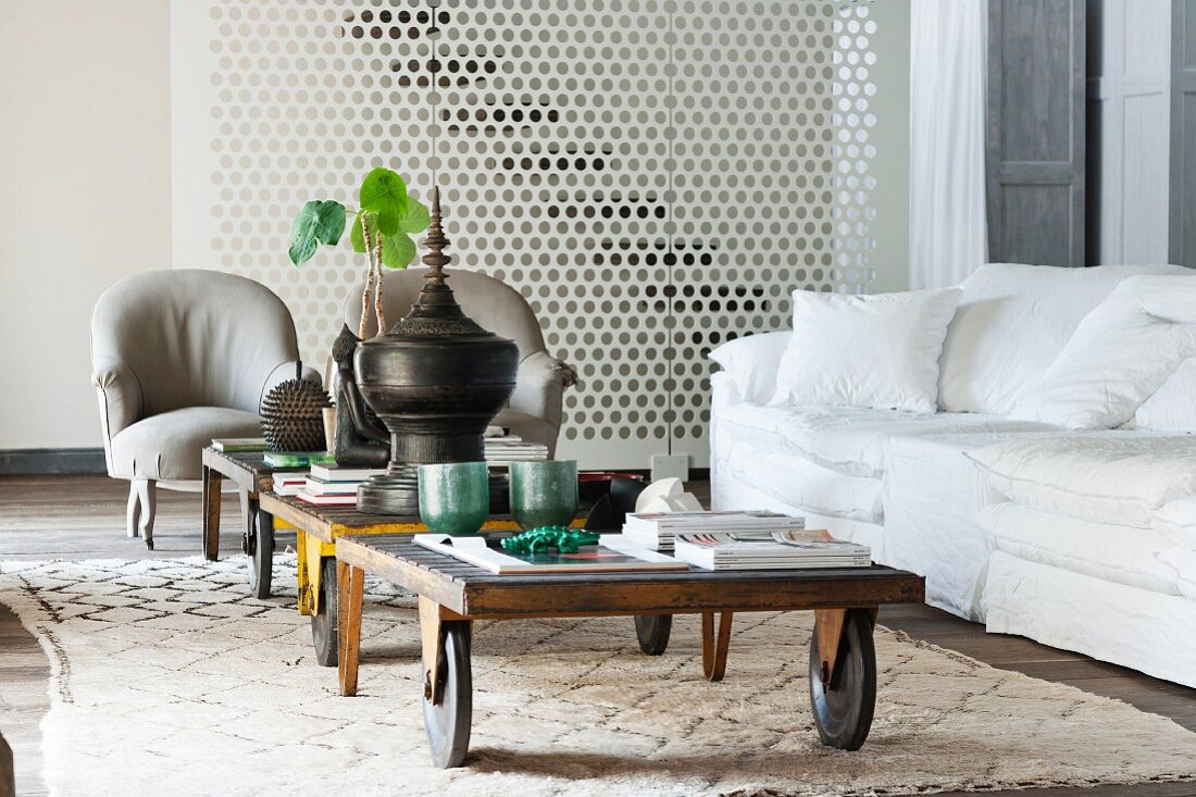 Old luggage carts used as coffee tables on Moroccan rug in front of white couch and grey armchairs