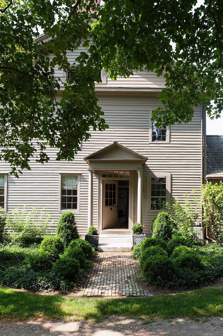 Eingang mit Vordach eines georgianischen Wohnhauses in Massachusetts mit sommerlichem Vorgarten