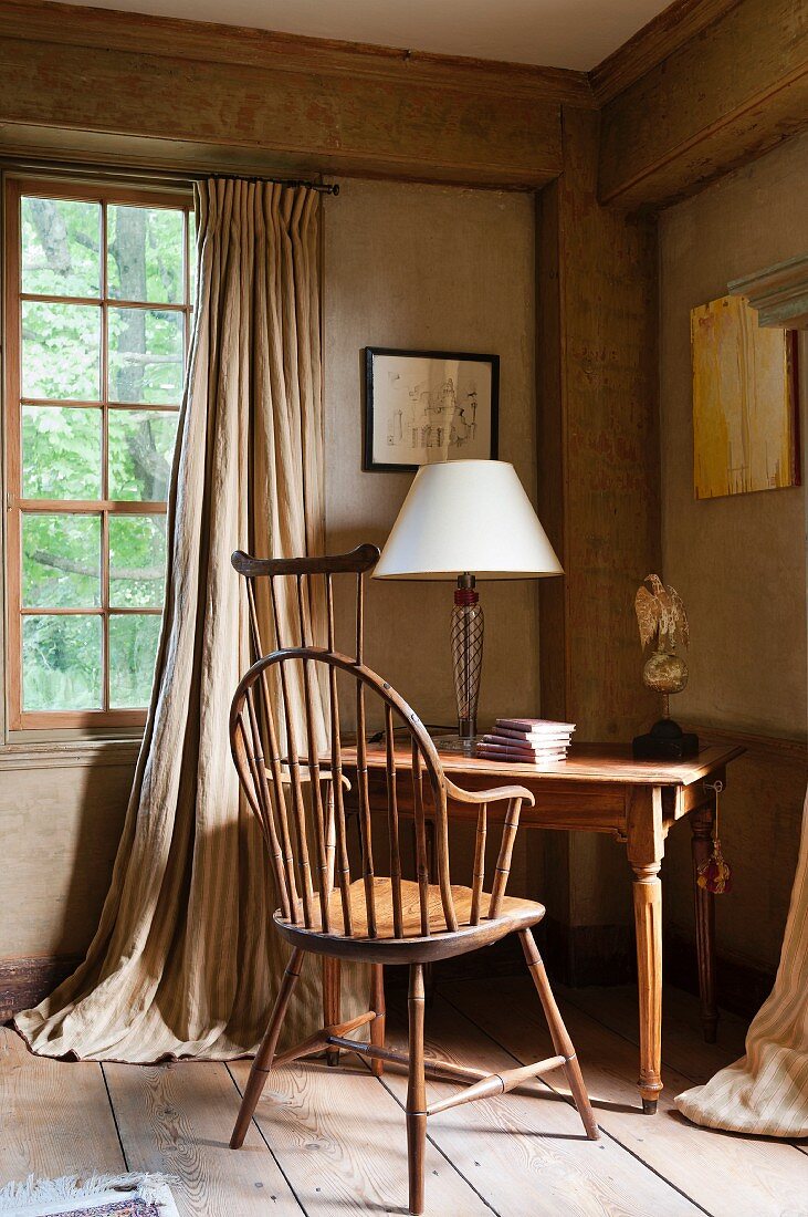 Desk with table lamp in corner of room in Georgian country house with lattice window and floor-length curtains