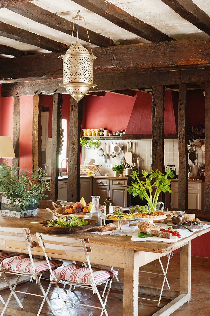 Grosse Wohnküche im französischen Landhaus mit Holztisch