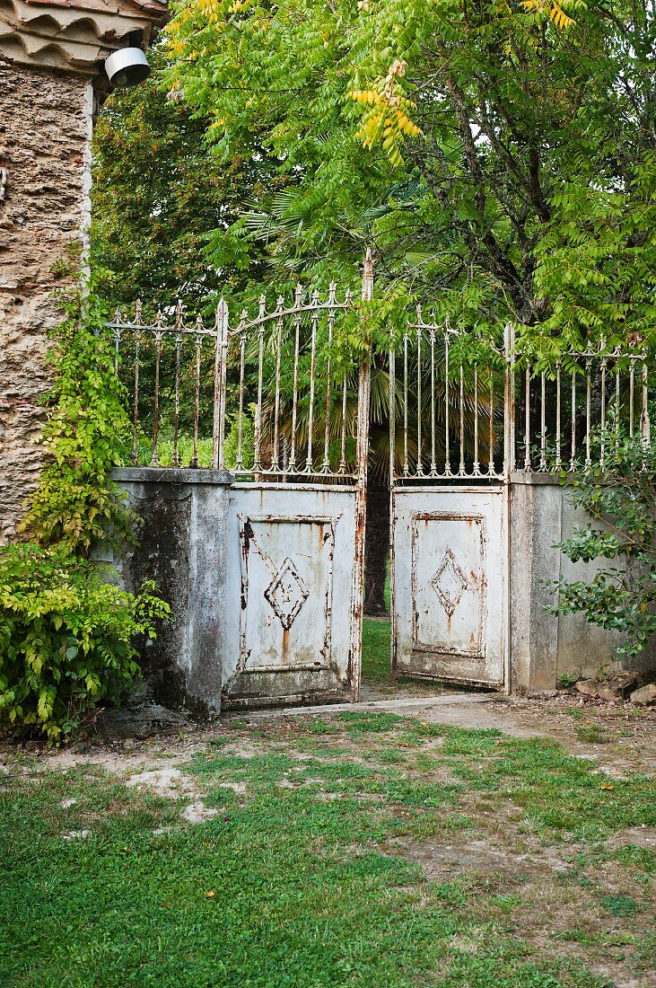 Traditional, rusty metal fence with half-open gate