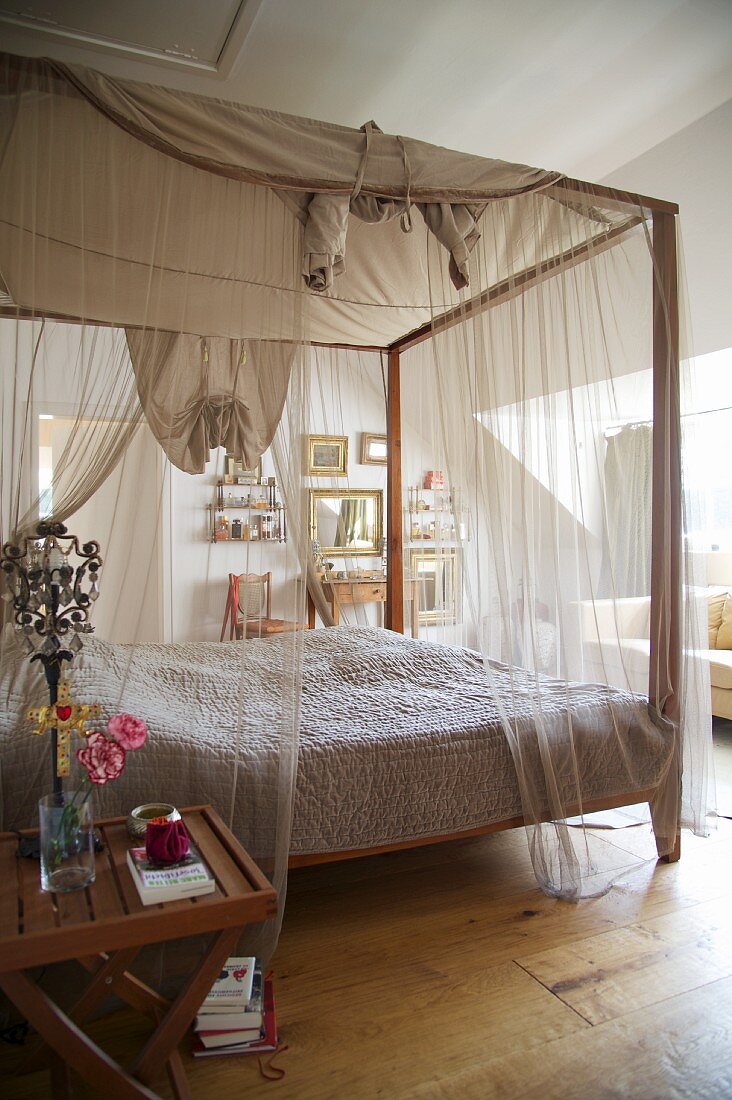 Romantic canopied bed with translucent curtain material in rustic interior