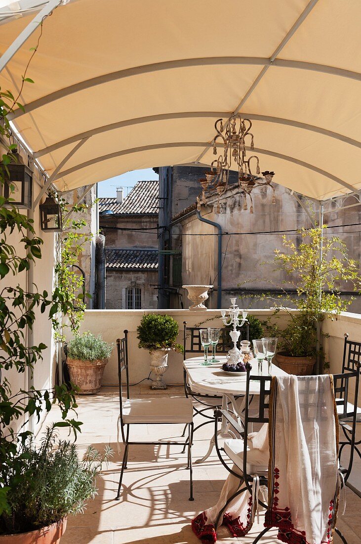 Summery terrace seating area with planters below awning in urban, French courtyard