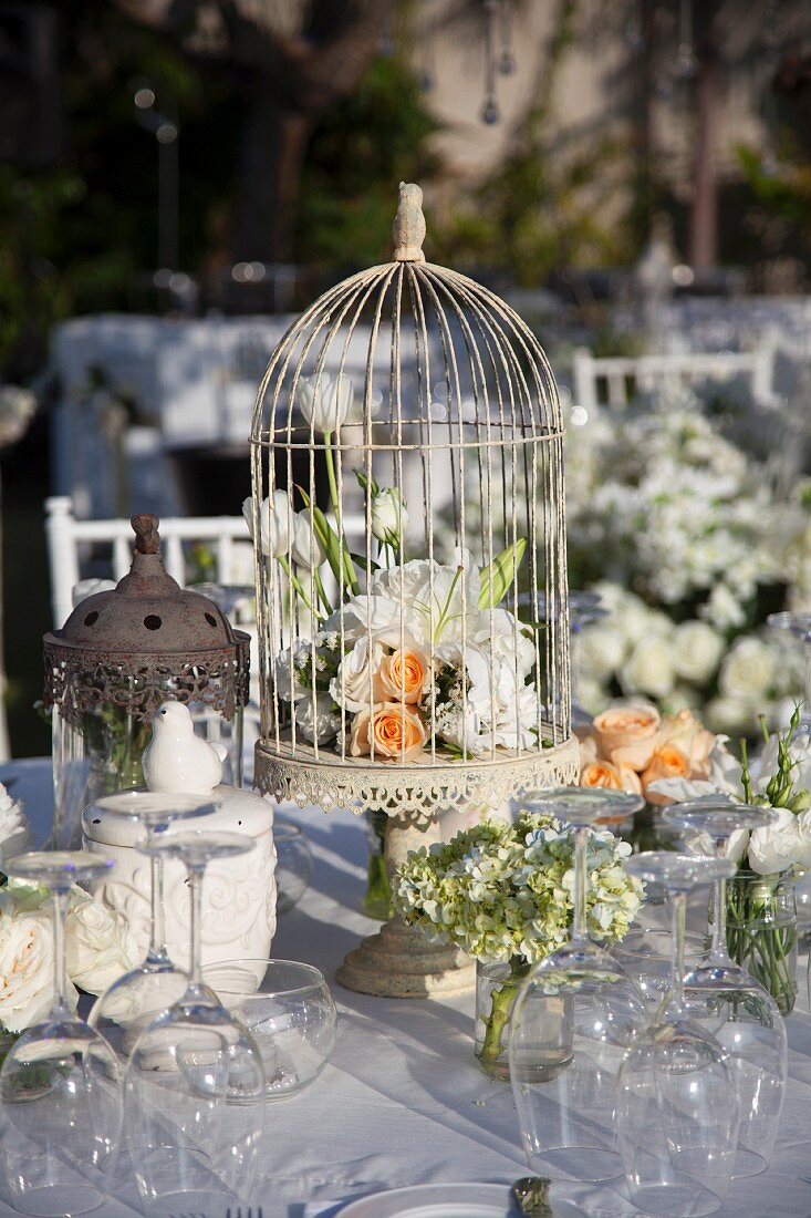 Hochzeitstisch mit Vogelkäfig und Blumendekoration im Freien