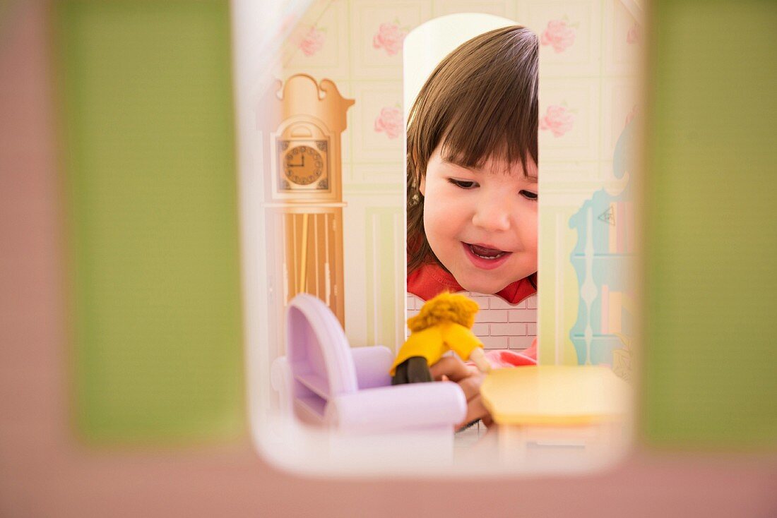 Kleines Mädchen spielt mit Puppenhaus