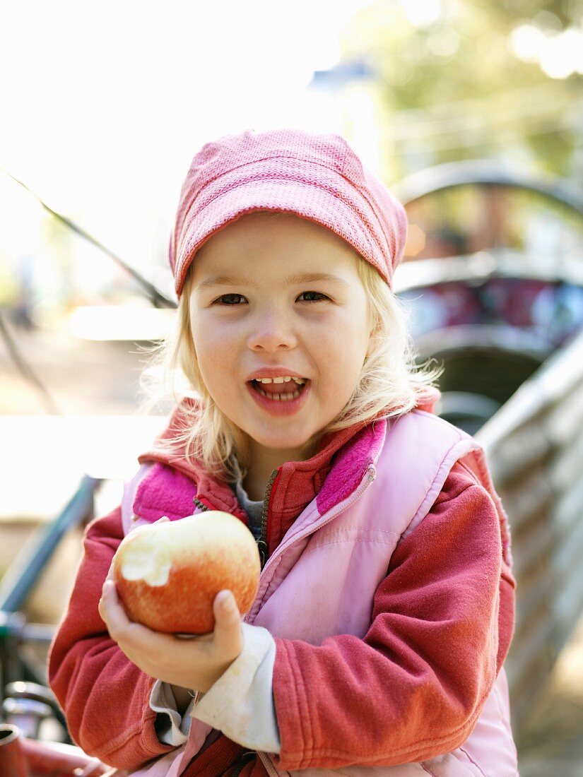 Kleines Mädchen isst einen Apfel im Freien