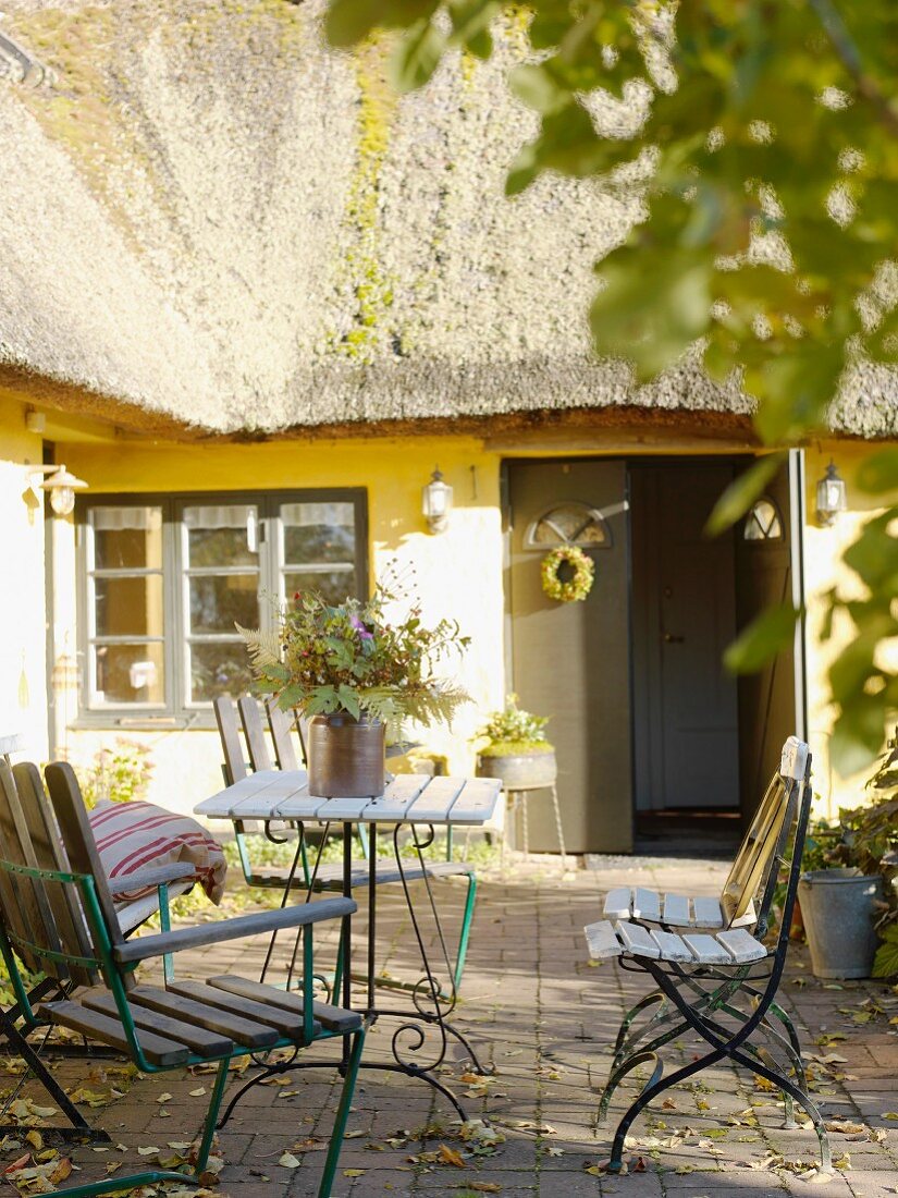 Gartenmöbeln auf der Terrasse eines reetgedeckten schwedischen Landhauses