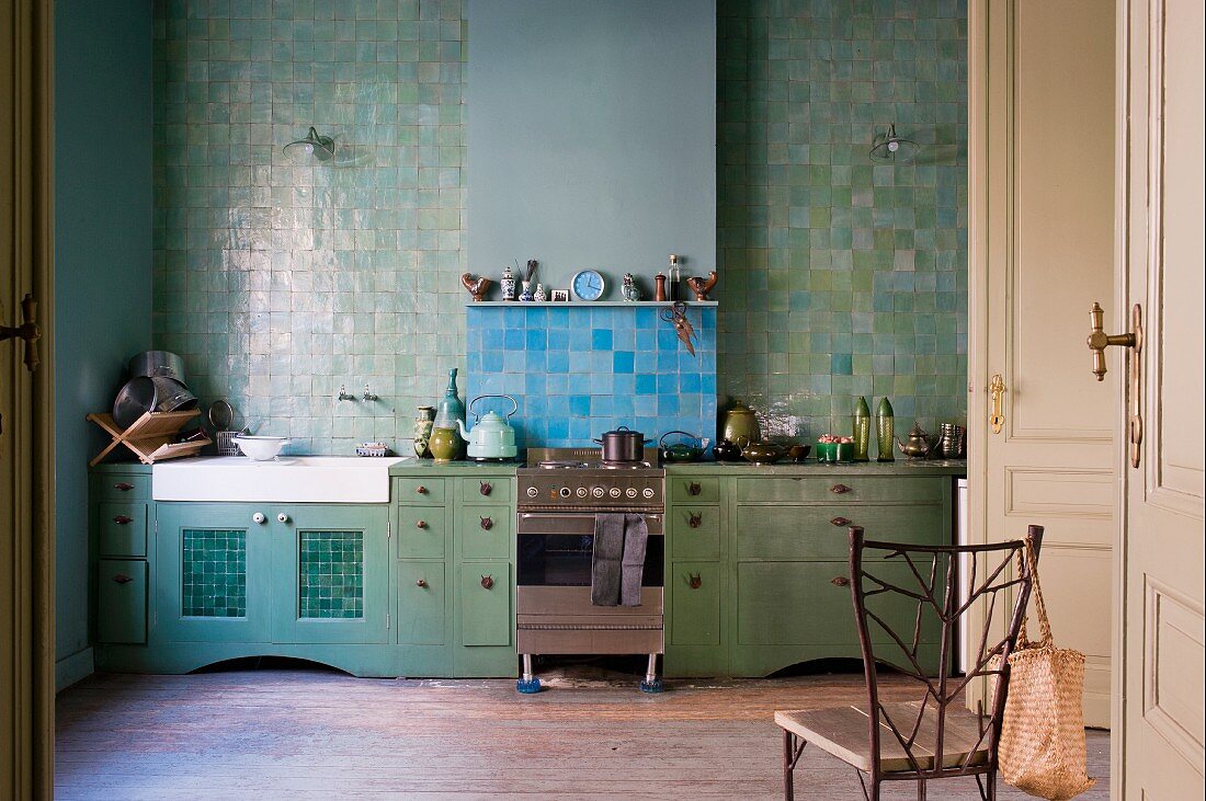 Küchenzeile mit grünen Schränken vor grüner Fliesenwand