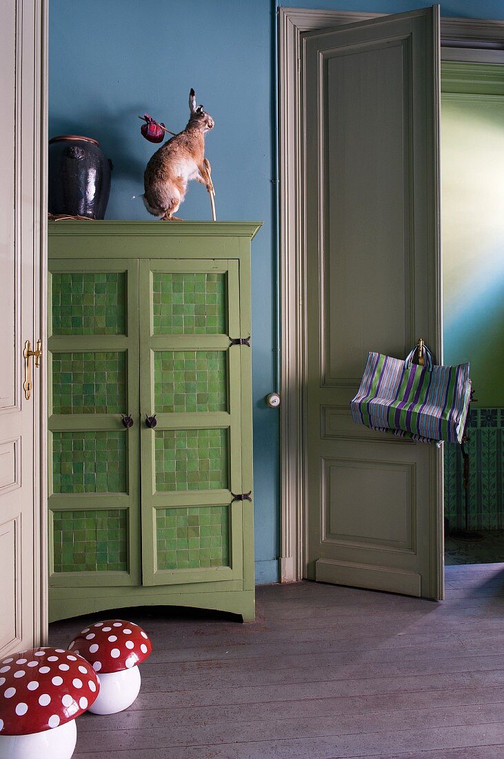 Interior with blue walls, green cabinet and hare & mushroom ornaments