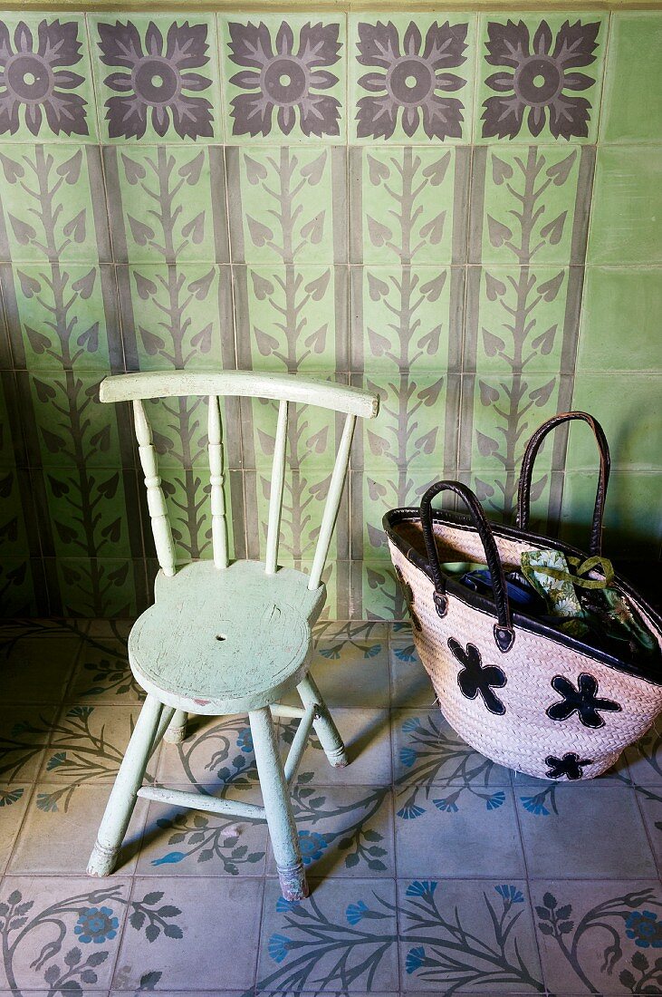 Einkaufstasche auf Fliesenboden neben altem Holzstuhl vor grün gefliester Wand