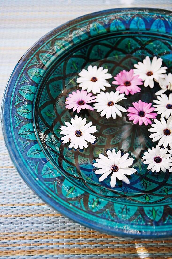 Flowers floating in ornate ceramic bowl in shades of blue
