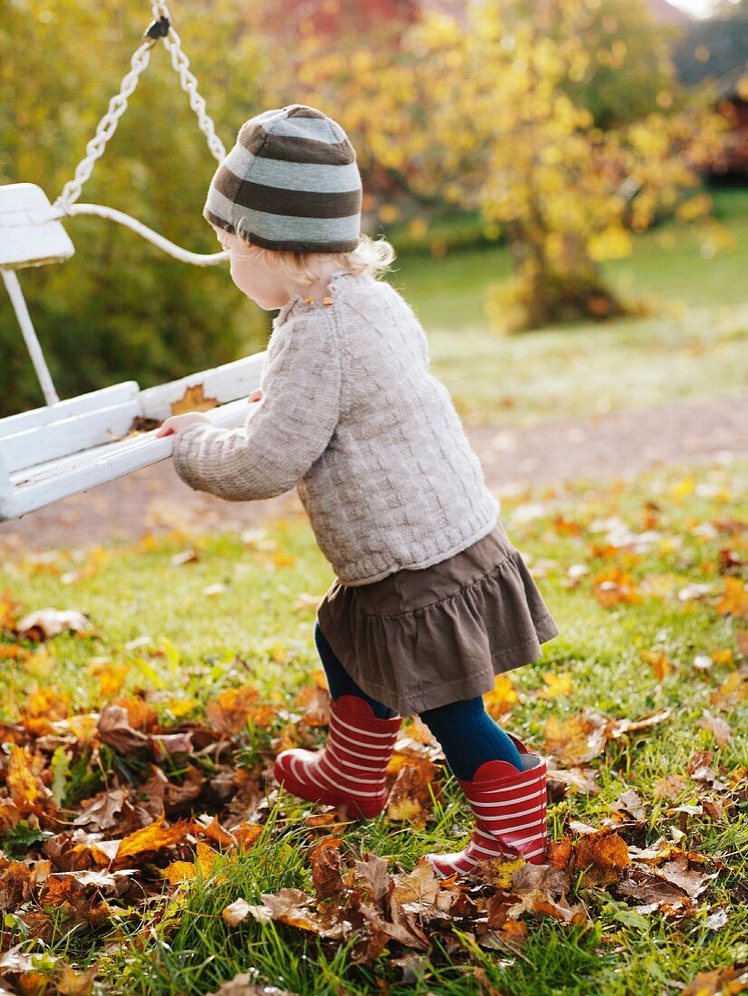 Kind spielt mit einer Schaukel im Garten bei Herbststimmung