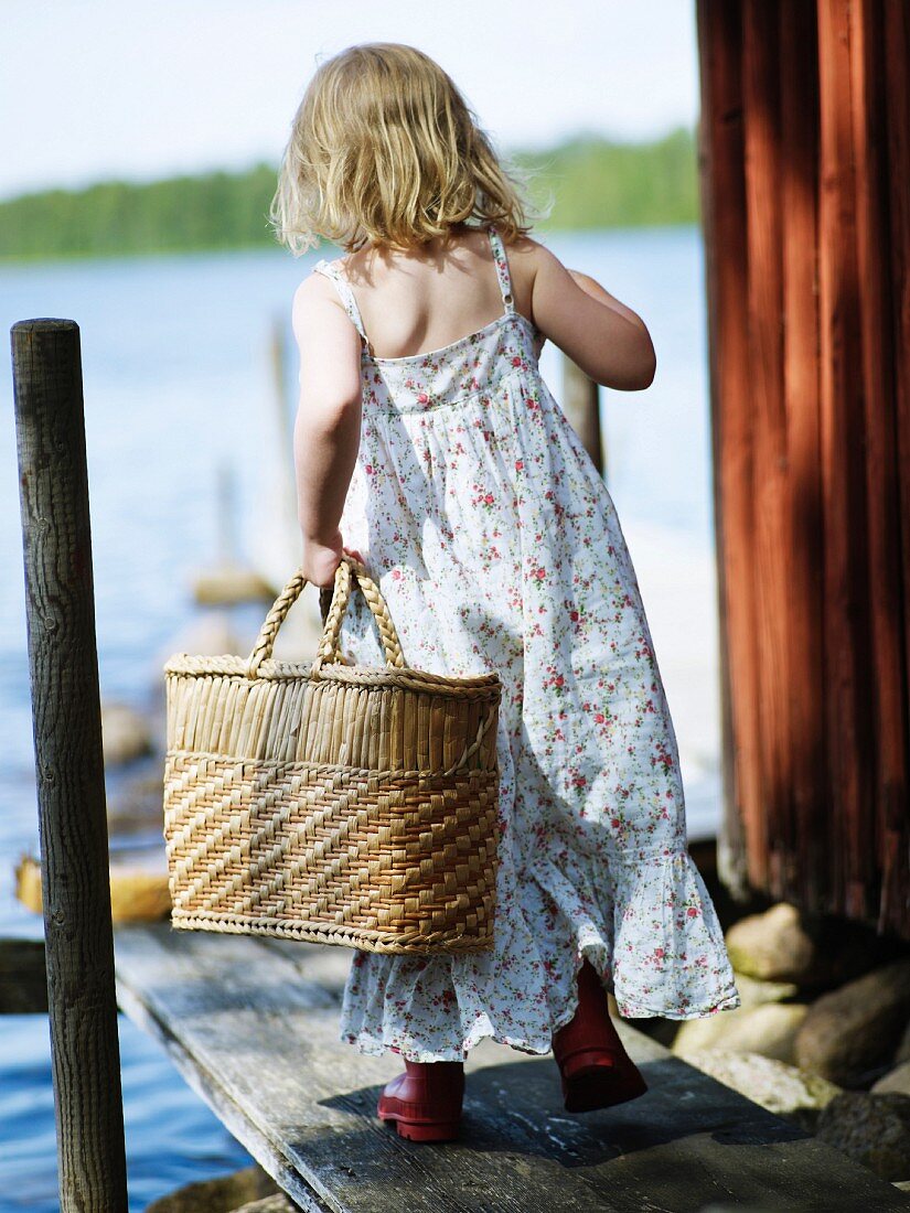 Mädchen mit Korbtasche auf einem Bootssteg