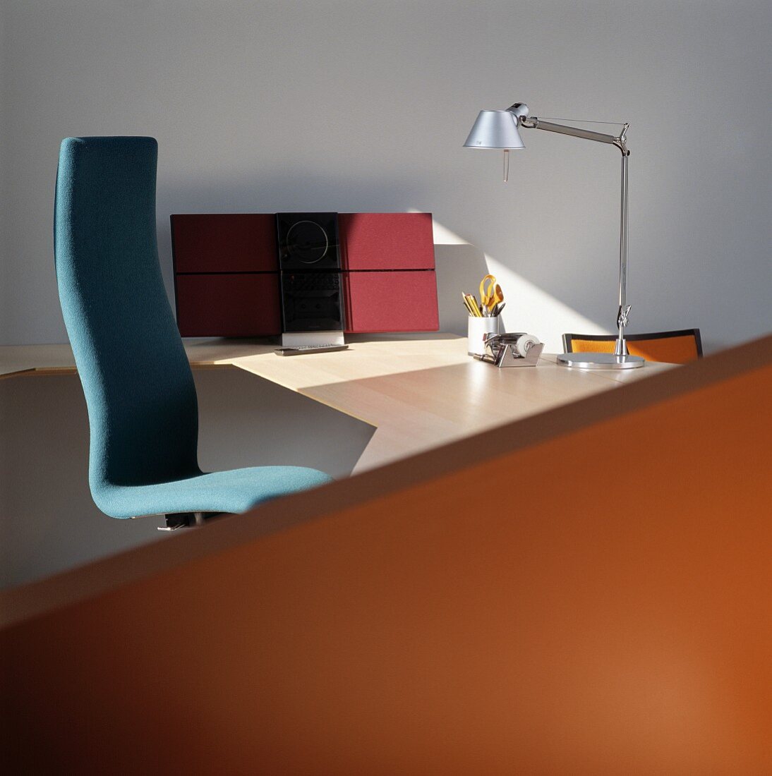 Blauer Bürostuhl an modernem Schreibtisch mit Designer Tischleuchte