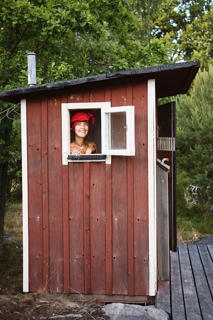 Schwedisches Badehäuschen, lachende Frau mit Handtuchturban am Fenster